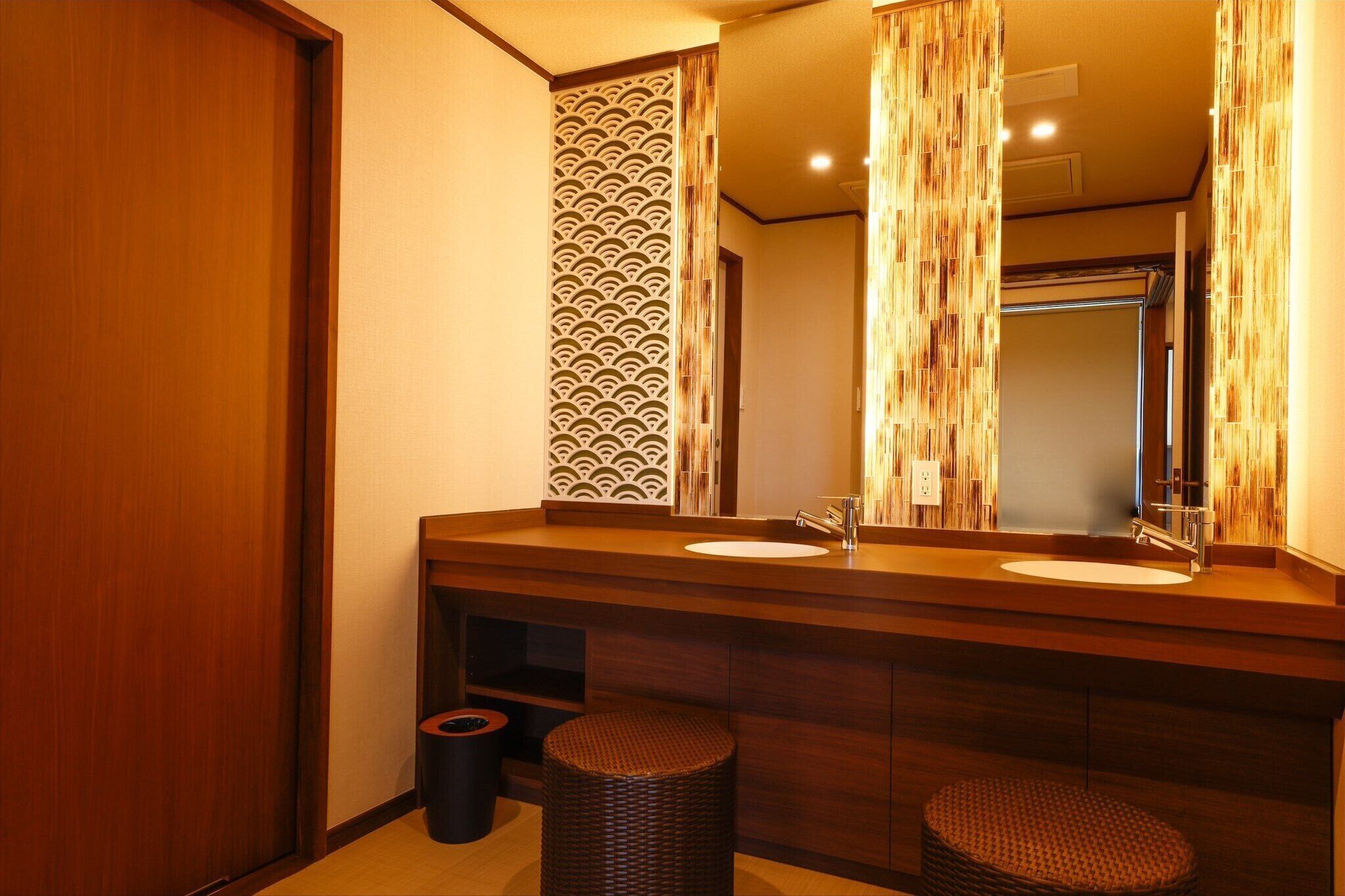 Un baño moderno con tocador de madera, dos lavamanos y un espejo grande.