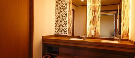 A modern bathroom with a wooden vanity, two sinks, and a large mirror.