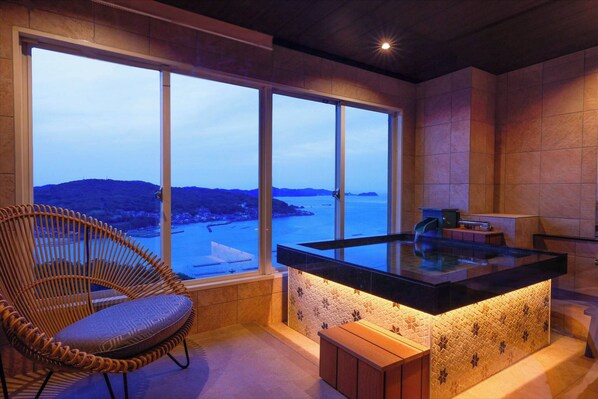 A modern kitchen with a large window, a glass-top island, and a wicker chair. - Toba View Hotel Hanashinjyu (Toba)