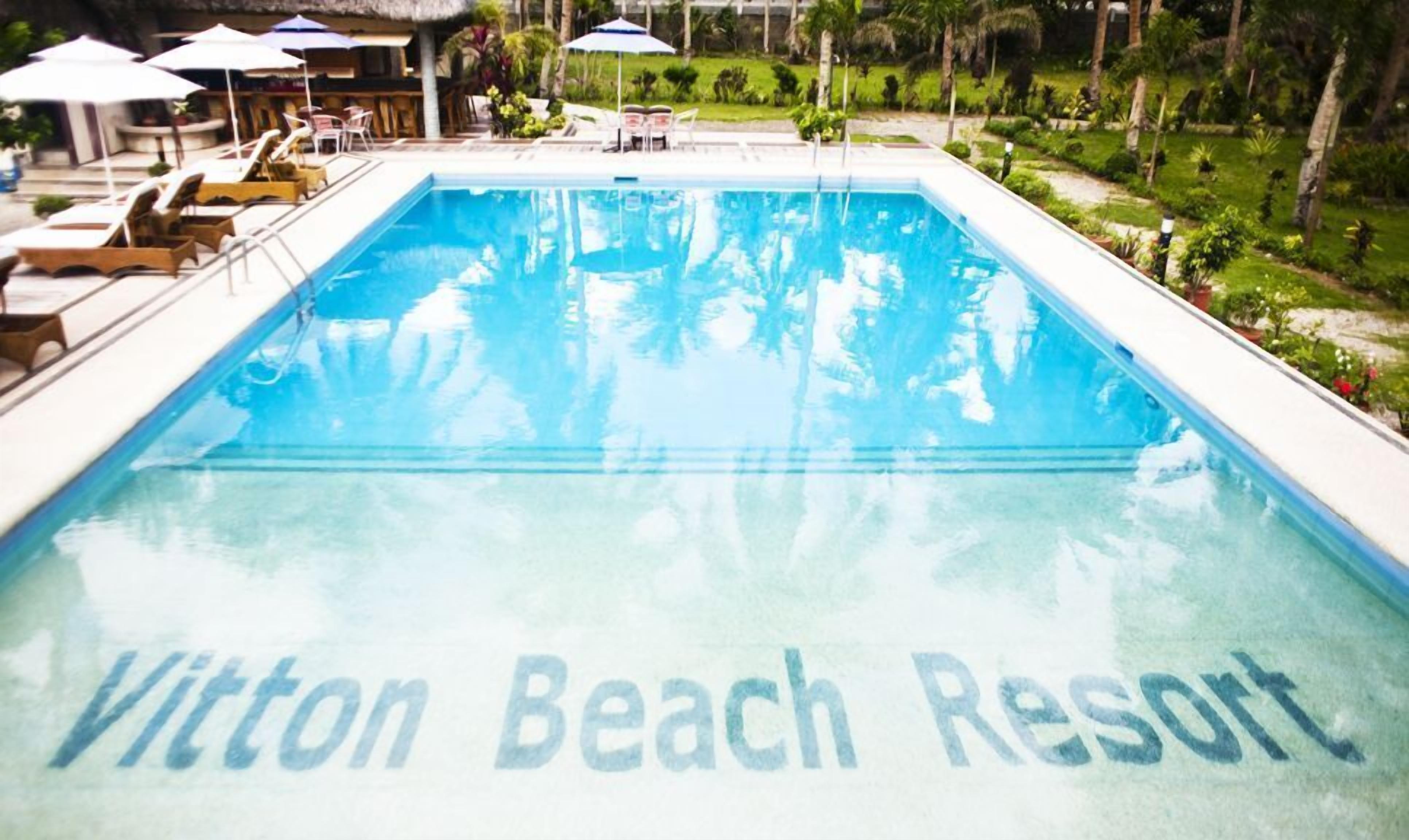 A swimming pool at Vittelton Beach Resort with lounge chairs and umbrellas.