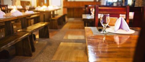 Un restaurante con mesas y bancos de madera, dispuesto en un ambiente acogedor y tenuemente iluminado.