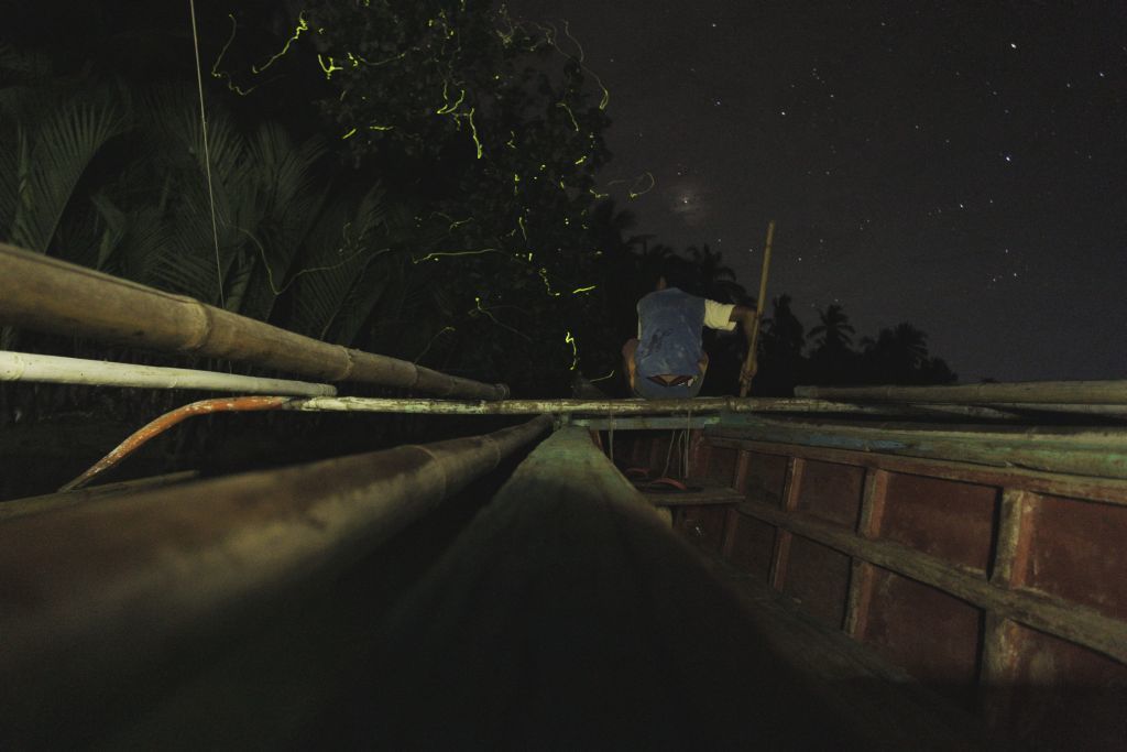 A nighttime view from a bridge with a wooden railing and a metal structure overhead.