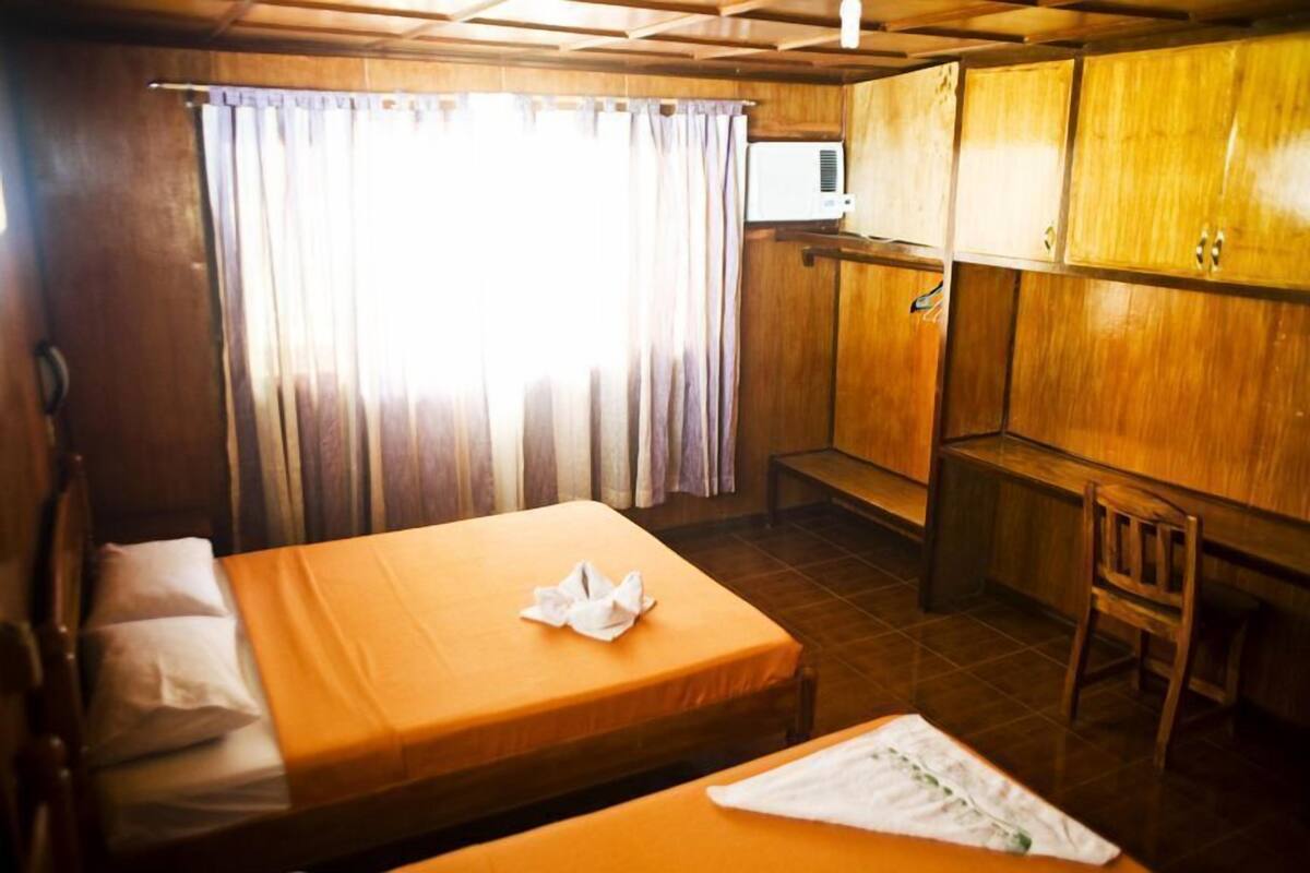 Une chambre avec deux lits, une armoire en bois, une petite table et une chaise.