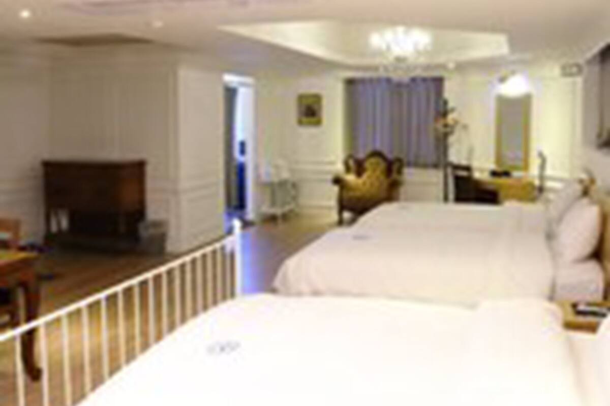 Ein Hotelzimmer mit einem großen Bett, einem Sessel, einem Schreibtisch und einer Chandelier.