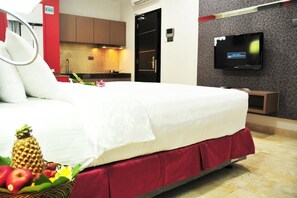 A hotel room with a bed, a television, a kitchen area, and a fruit basket. - The Centro Hotel & Residence by Orchardz (Batam)