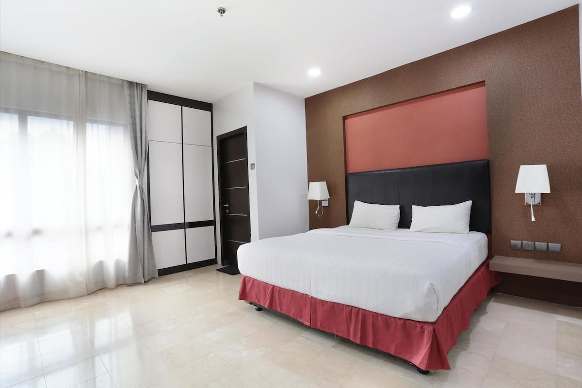A modern hotel room with a large bed, a wardrobe, and a bathroom.
