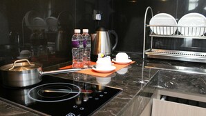 A modern kitchen with a built-in induction cooktop, a coffee maker, and a dish drying rack.