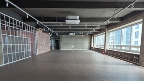 Tilava sisätila, jossa on betonilattia, suuret ikkunat toisella seinällä ja tiiliseinä toisella.