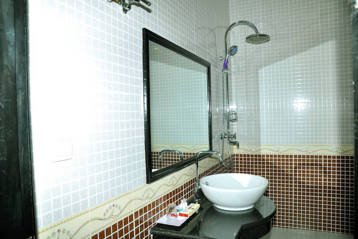 Un baño con lavamanos blanco, un espejo y una ducha.