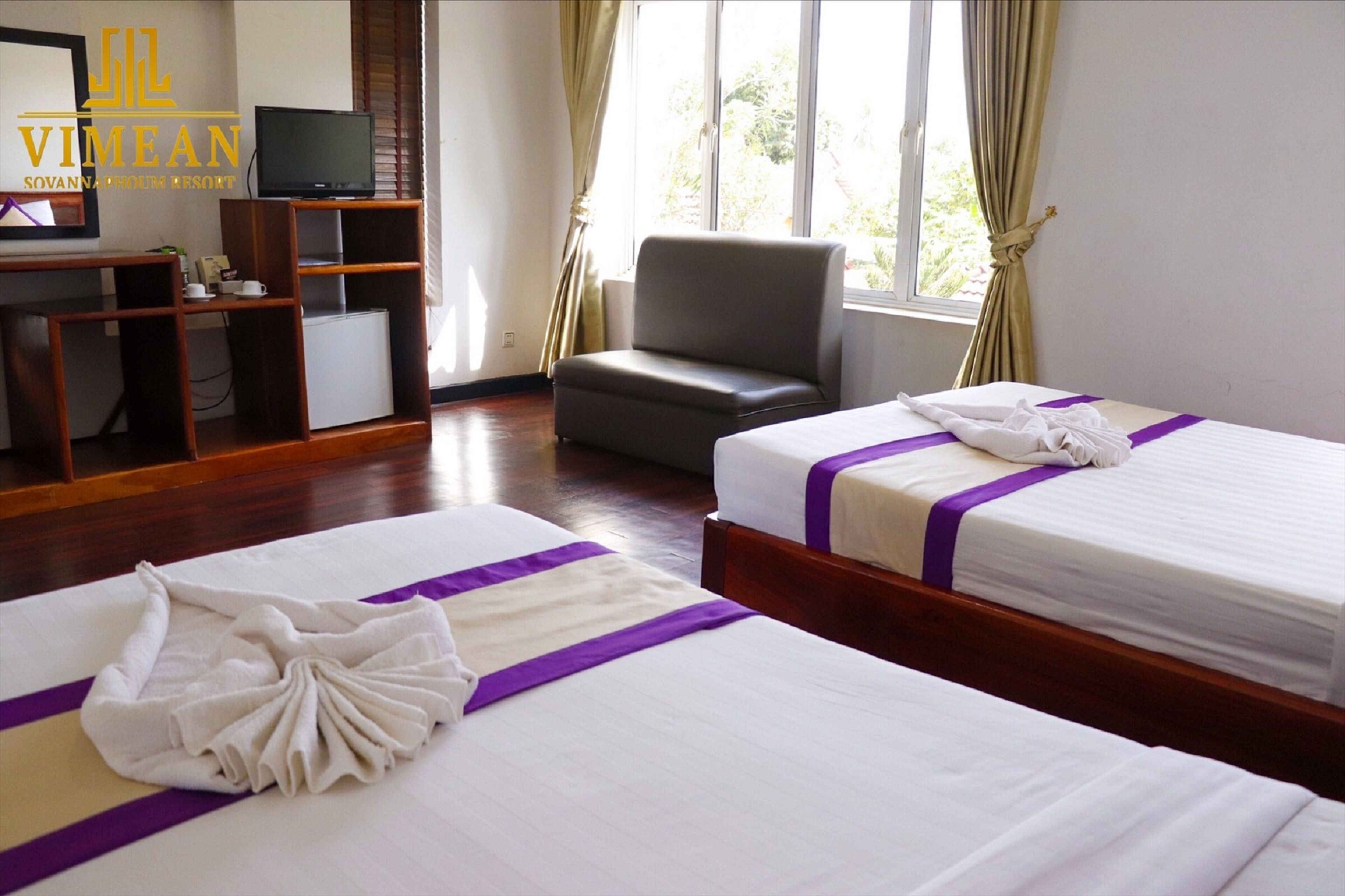 Habitación de hotel con dos camas, televisión, escritorio y una silla.