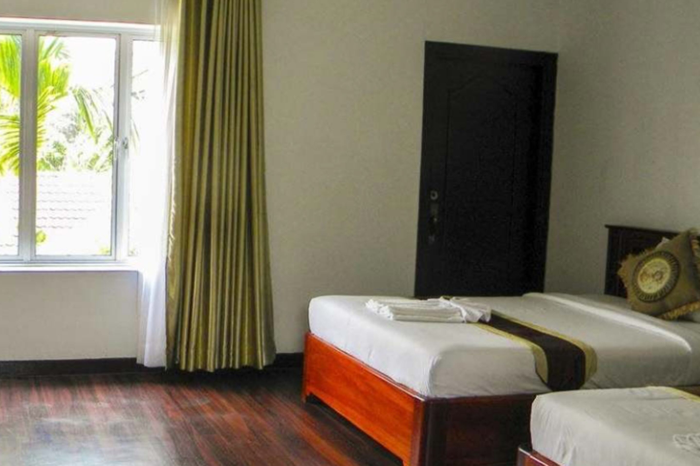 Una habitación de hotel con dos camas, una ventana con cortinas y una puerta.