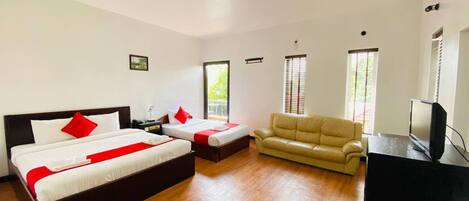 Habitación de hotel con dos camas, un sofá, un televisor y ventanas amplias.