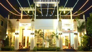 A hotel entrance with a central statue, two balconies, and a well-lit facade. - Vimean Sovannaphoum Resort (Battambang)