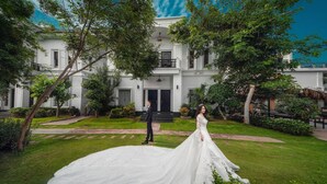 A wedding scene in front of a large, white building with a grand entrance and a well-maintained garden. - Vimean Sovannaphoum Resort (Battambang)