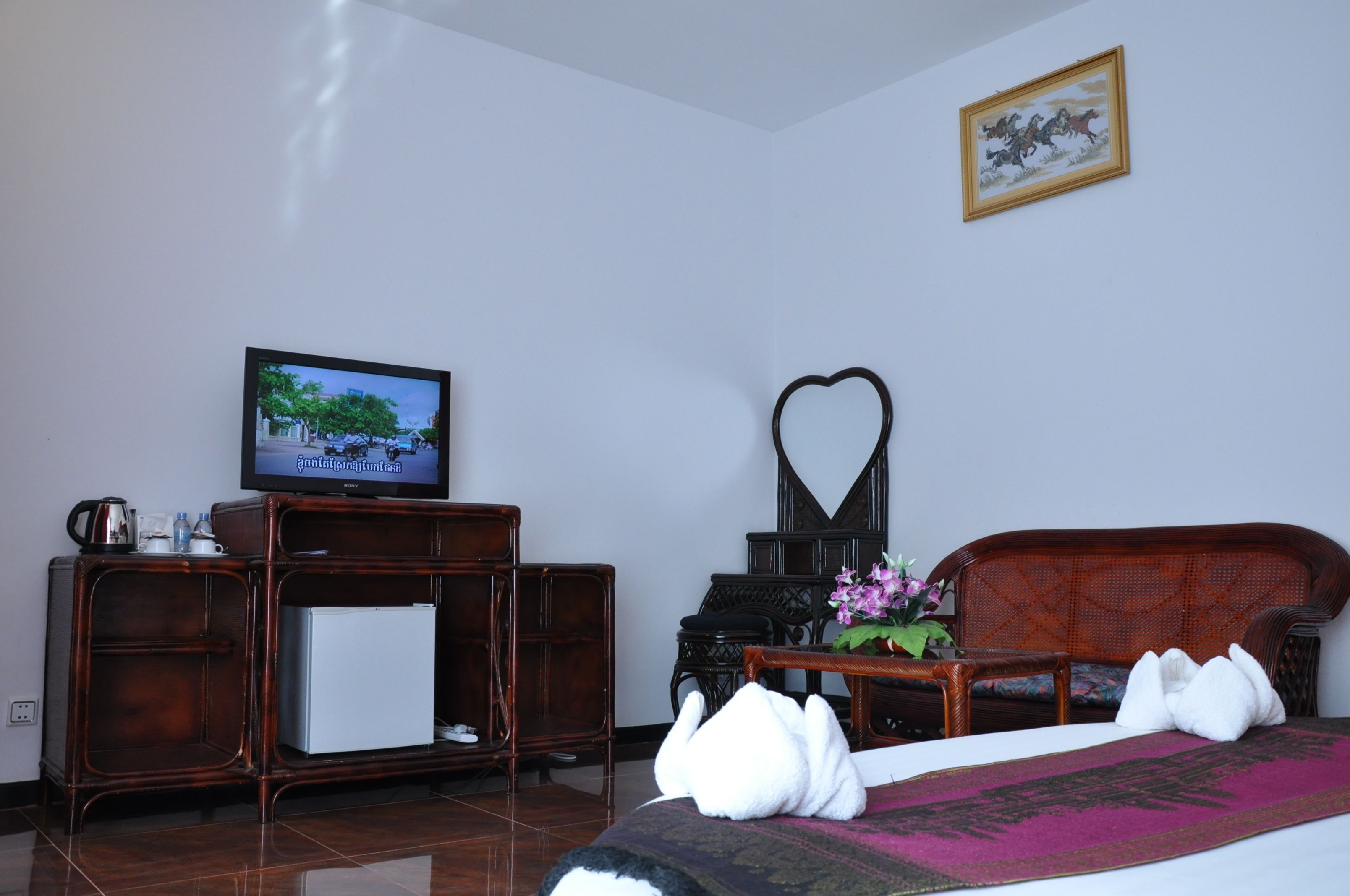 Habitación de hotel con televisión, una decoración con forma de corazón, sofá y cama con almohada decorativa.