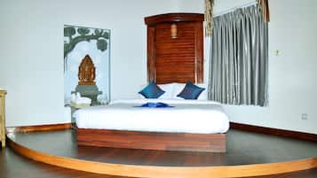 Un dormitorio con una cama de madera curvada, cabecera de madera, una lámpara de pared y un ventanal con cortinas.
