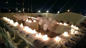 A tented outdoor dining area with tables set for a meal, candles, and balloons. - Gandhi Inn (Medan)