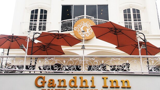 A white building with balconies and a sign reading "Gandhi Inn Homey Concept & Cafe". - Gandhi Inn (Medan)