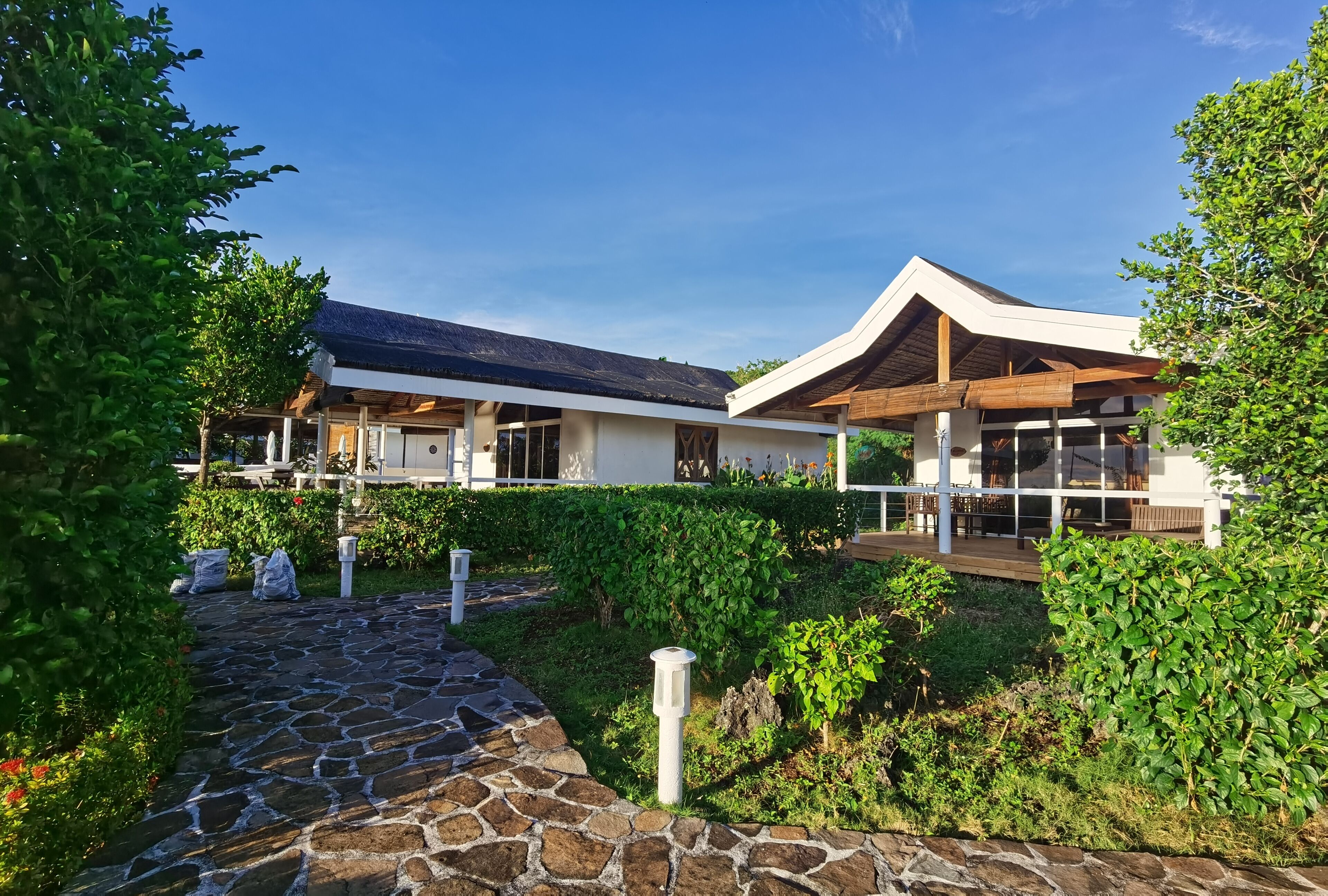 A modern building with a stone pathway leading to a covered patio area.