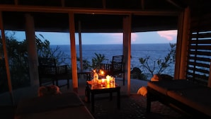 A cozy room with a table set for two, a bench, and a view of the ocean. - Kawayan Holiday Resort (San Juan)