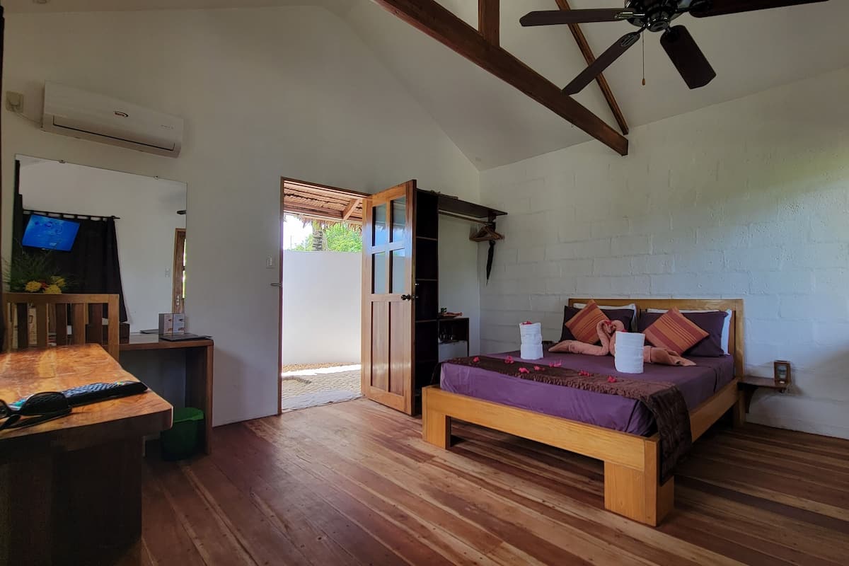 A bedroom with a wooden bed, a TV on a stand, and a ceiling fan.