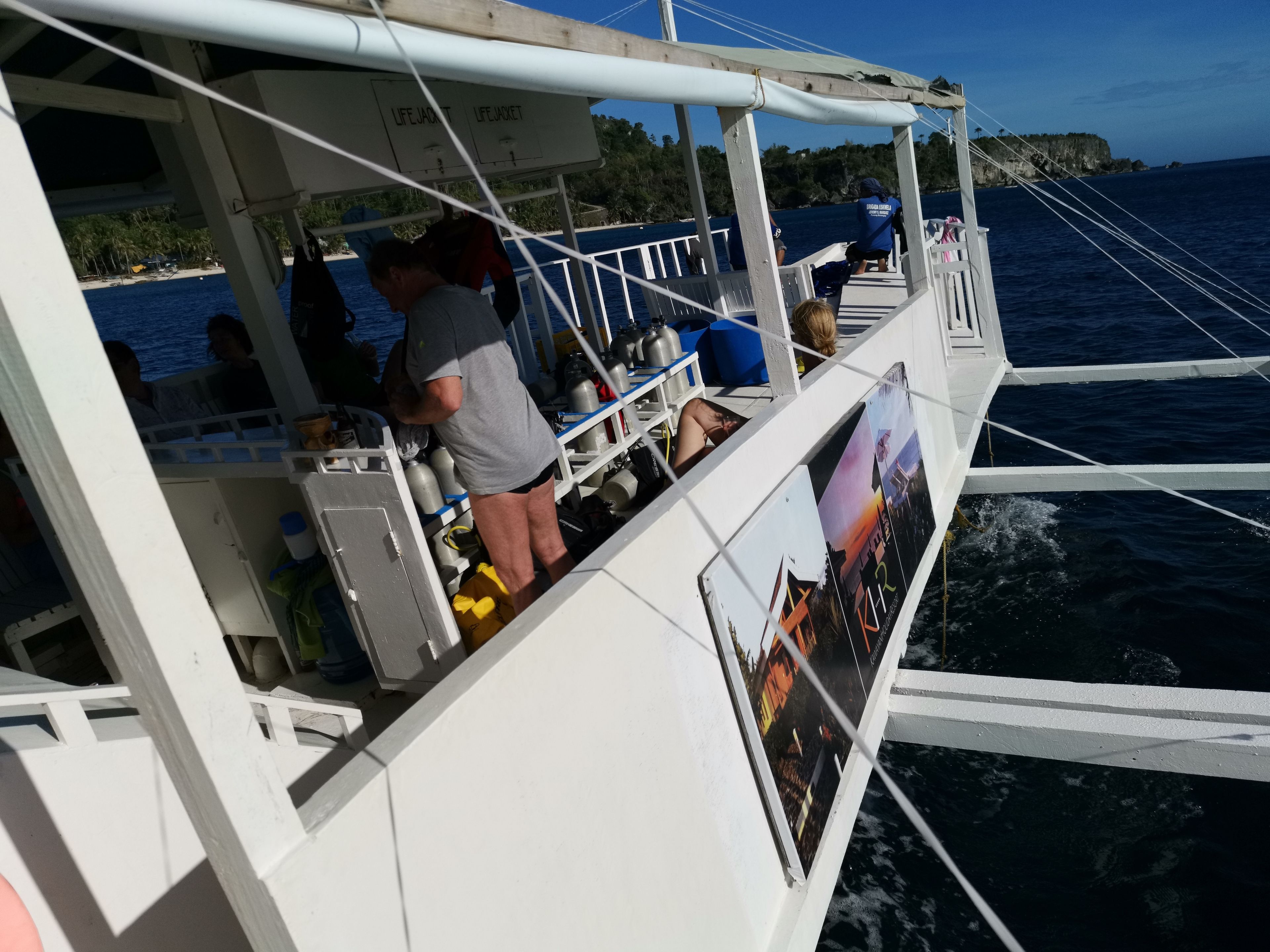A boat with a white exterior, life jackets, and a person standing by the railing.