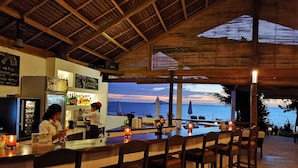 A bar area with a view of the ocean, wooden ceiling, and bar stools. - Kawayan Holiday Resort (San Juan)