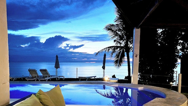 A pool with a view of the ocean and palm trees. - Kawayan Holiday Resort (San Juan)