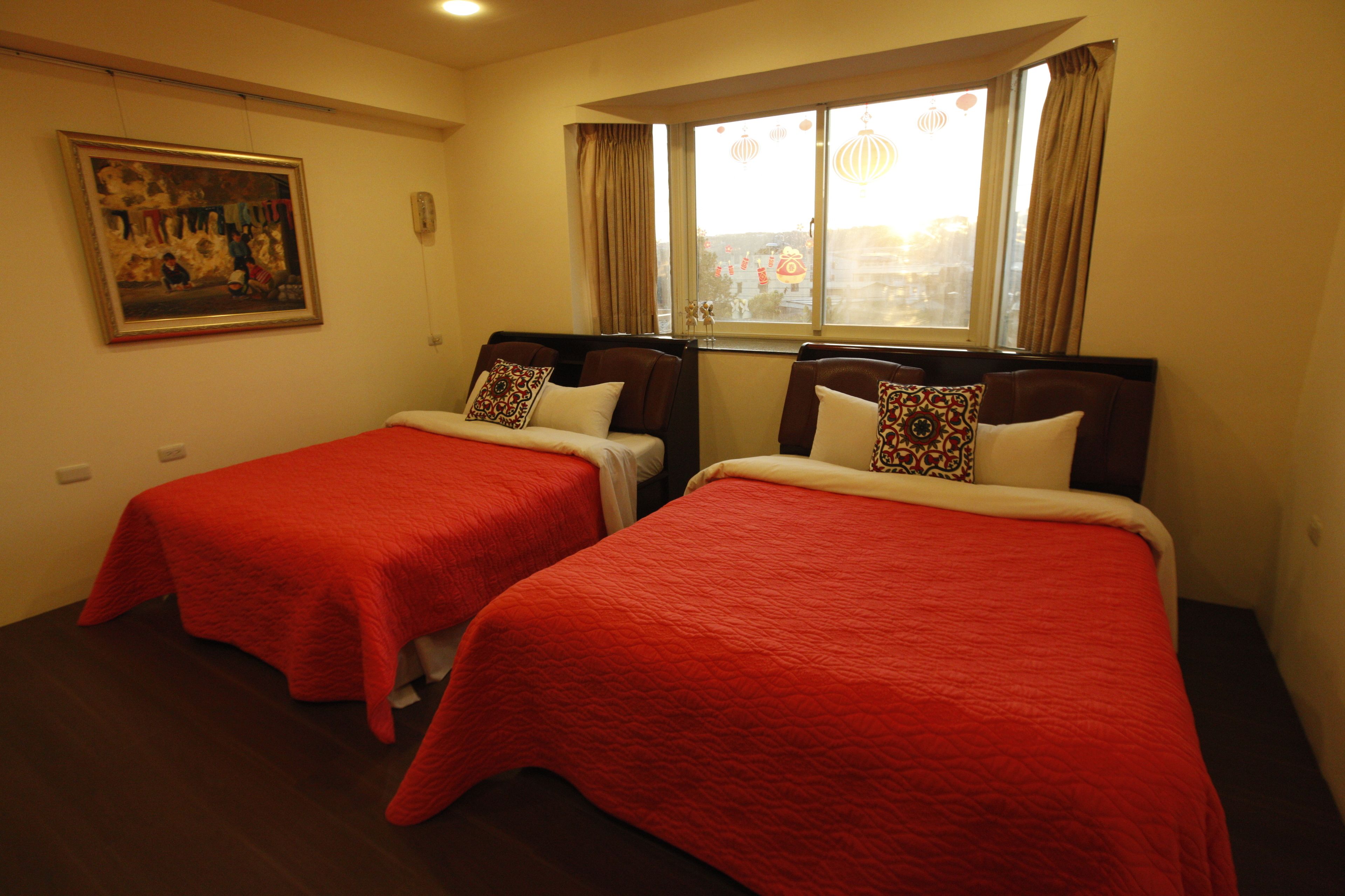 Habitación de hotel con dos camas, cada una con colcha y almohadas a juego. Hay un cuadro en la pared y una ventana con cortinas.