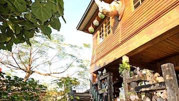 Uma casa de madeira com escadaria que leva a um alpendre, decorada com vários enfeites e plantas.