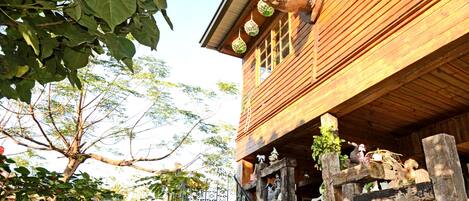A wooden house with a staircase leading to a porch, decorated with various ornaments and plants.