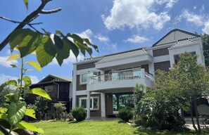 A two-story house with a balcony, surrounded by greenery and a clear sky. - Garden Life Homestay (Taichung)