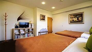 Ein Hotelzimmer mit zwei Betten, einem Fernseher, einem Bücherregal und Kunstwerken an den Wänden.