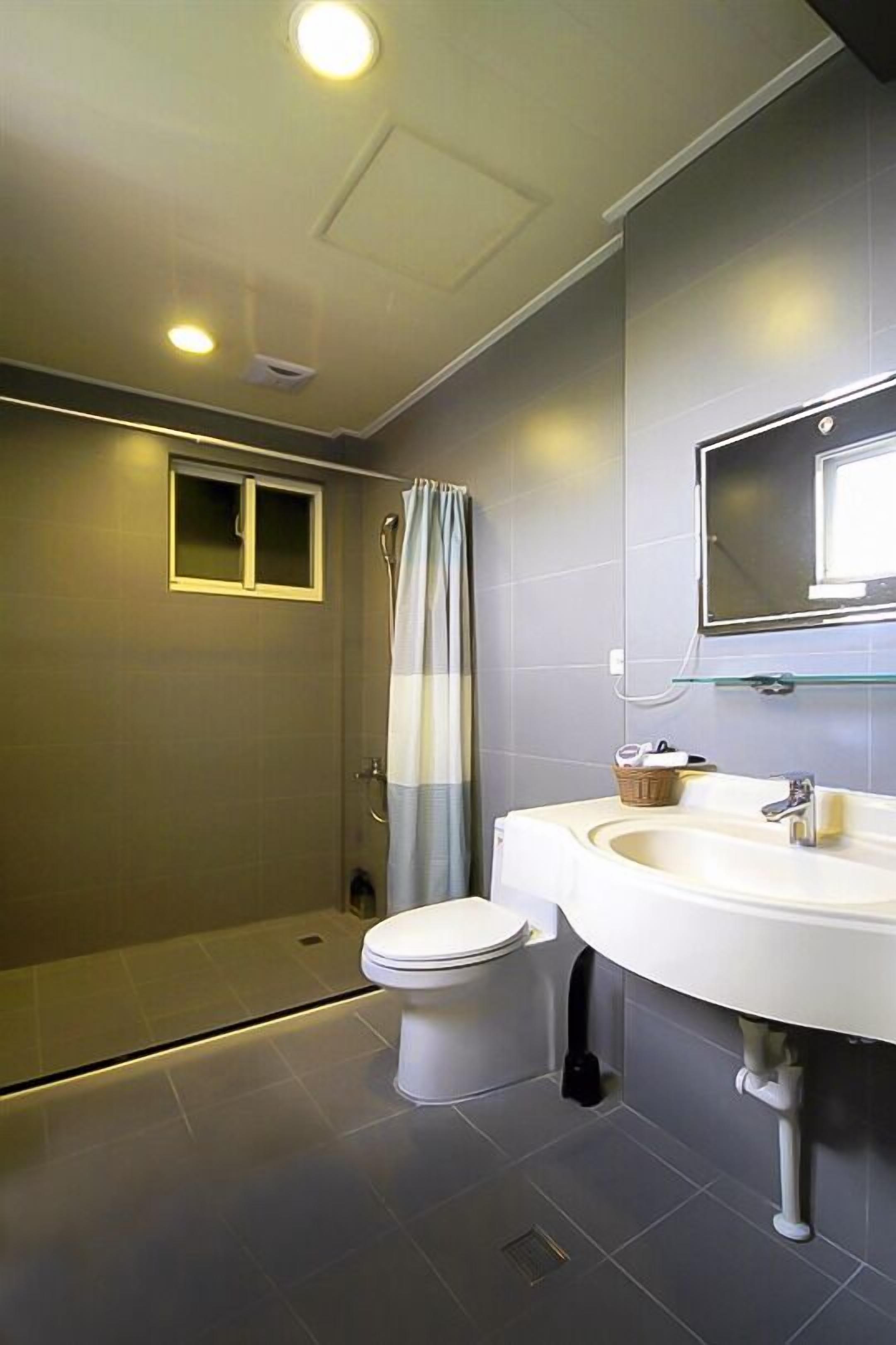 A modern bathroom with a toilet, sink, and shower.