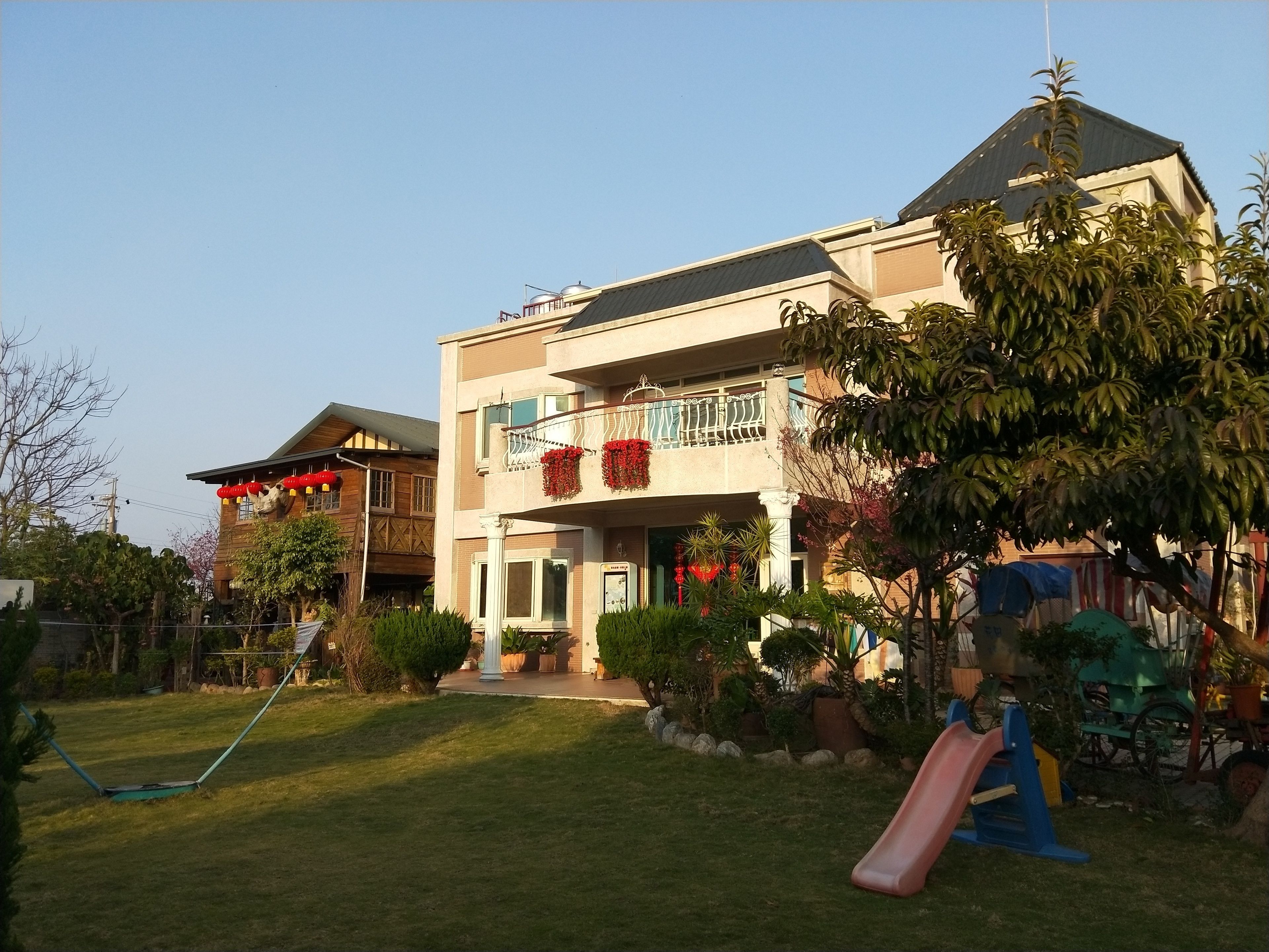 A two-story building with a balcony, a slide, and a well-maintained lawn.