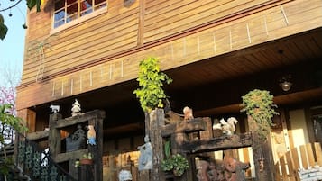 A wooden building with a traditional design, featuring a decorative wooden gate, potted plants, and a statue of a bird.