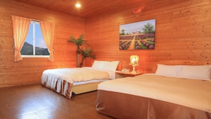 Una habitación de madera con dos camas, una ventana con cortinas, un cuadro de un viñedo y una pequeña mesa con una lámpara.