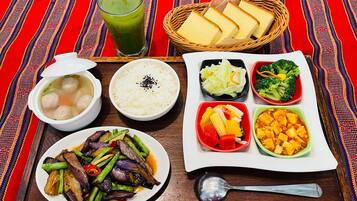 A meal tray with various dishes including meatballs in soup, rice, mixed vegetables, and a green drink.