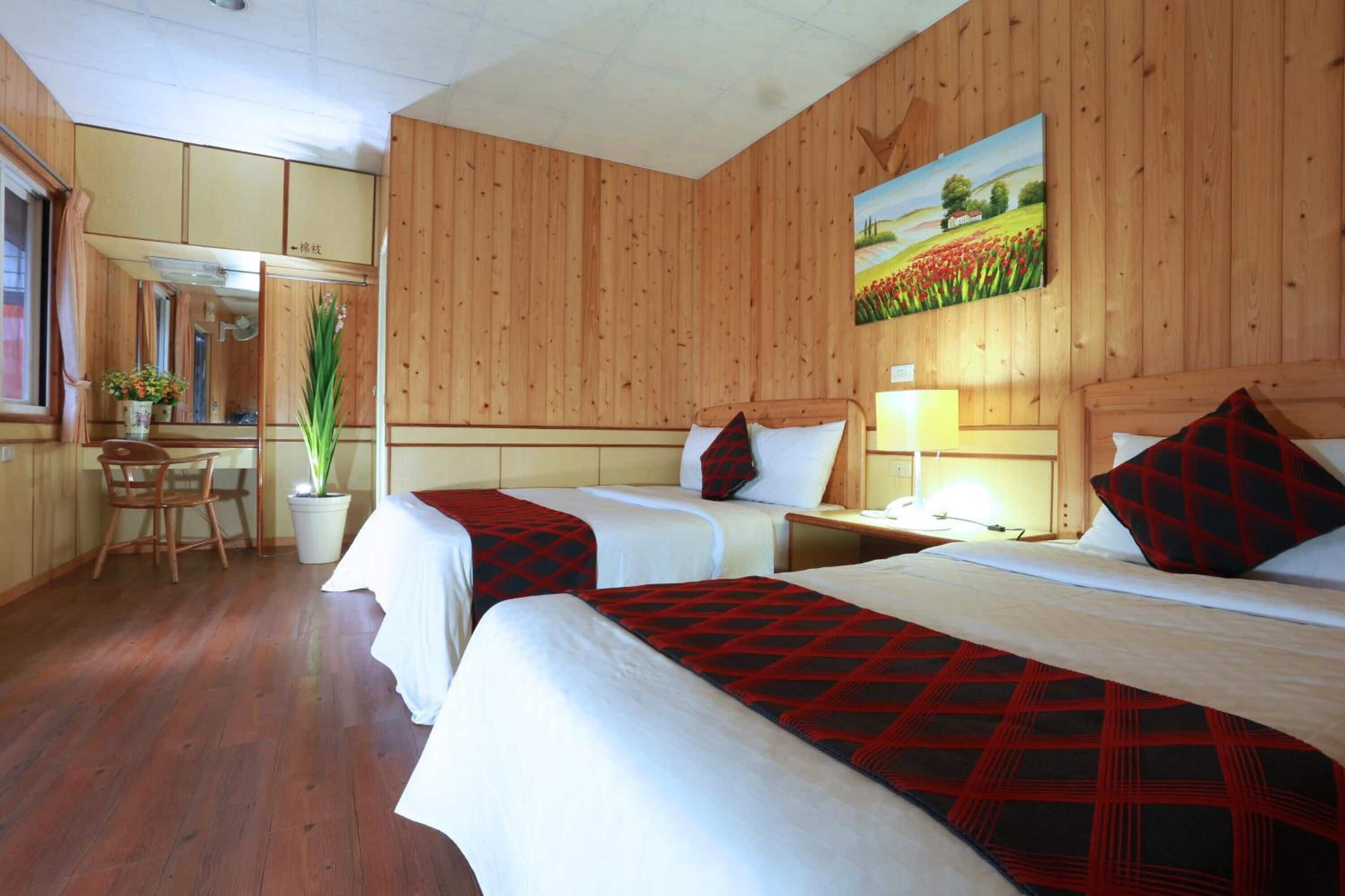 Una habitación de hotel con dos camas, paredes de madera, un cuadro, un escritorio y una silla.