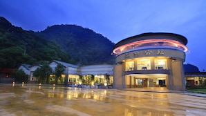 Un hotel con un edificio circular, una entrada bien iluminada y un reflejo en el suelo mojado.