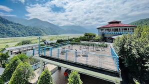Un restaurante con terraza al aire libre que ofrece vistas a un valle y montañas.