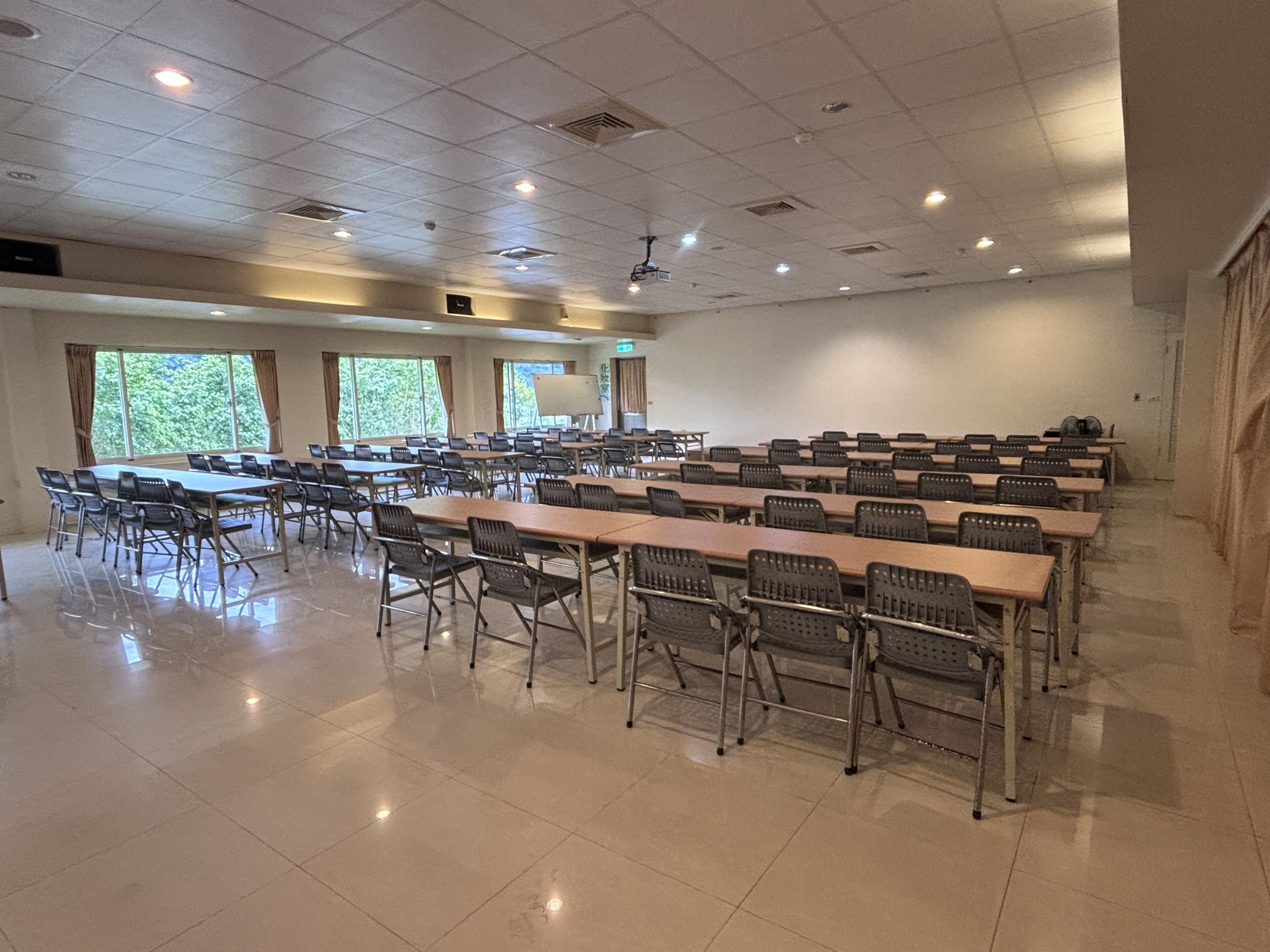 A conference room with long tables and chairs, large windows, and a whiteboard.