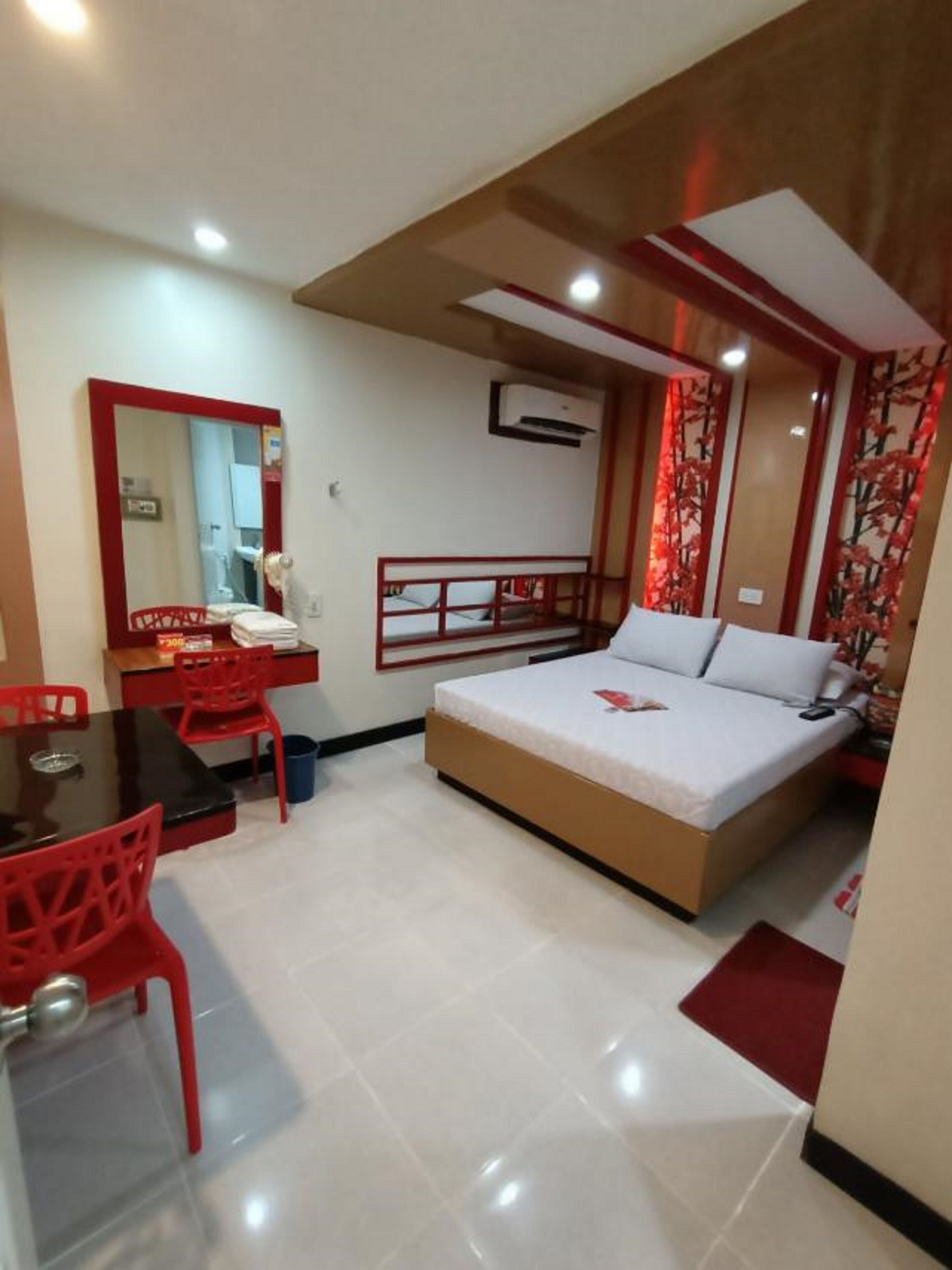 A bedroom with a bed, a desk, a chair, and a mirror.