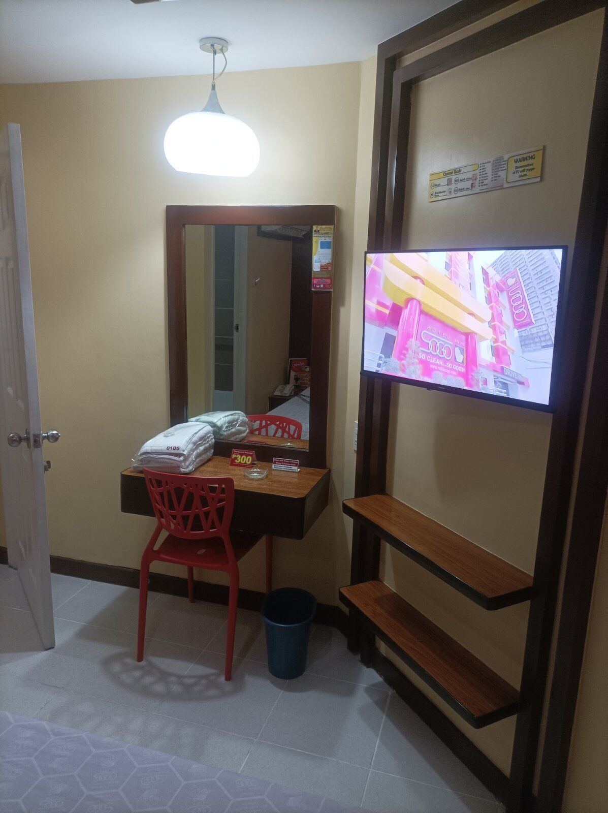 A hotel room with a desk, chair, and a television mounted on the wall.
