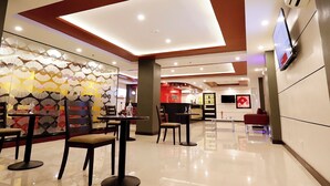A modern hotel lobby with a high ceiling, a seating area with tables and chairs, and a reception desk. - Hotel Sogo LRT Monumento Station (Caloocan)