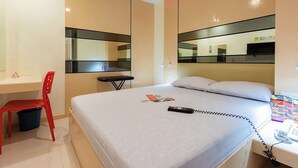 Habitación de hotel con una cama, un escritorio, una silla, un teléfono y un espejo.