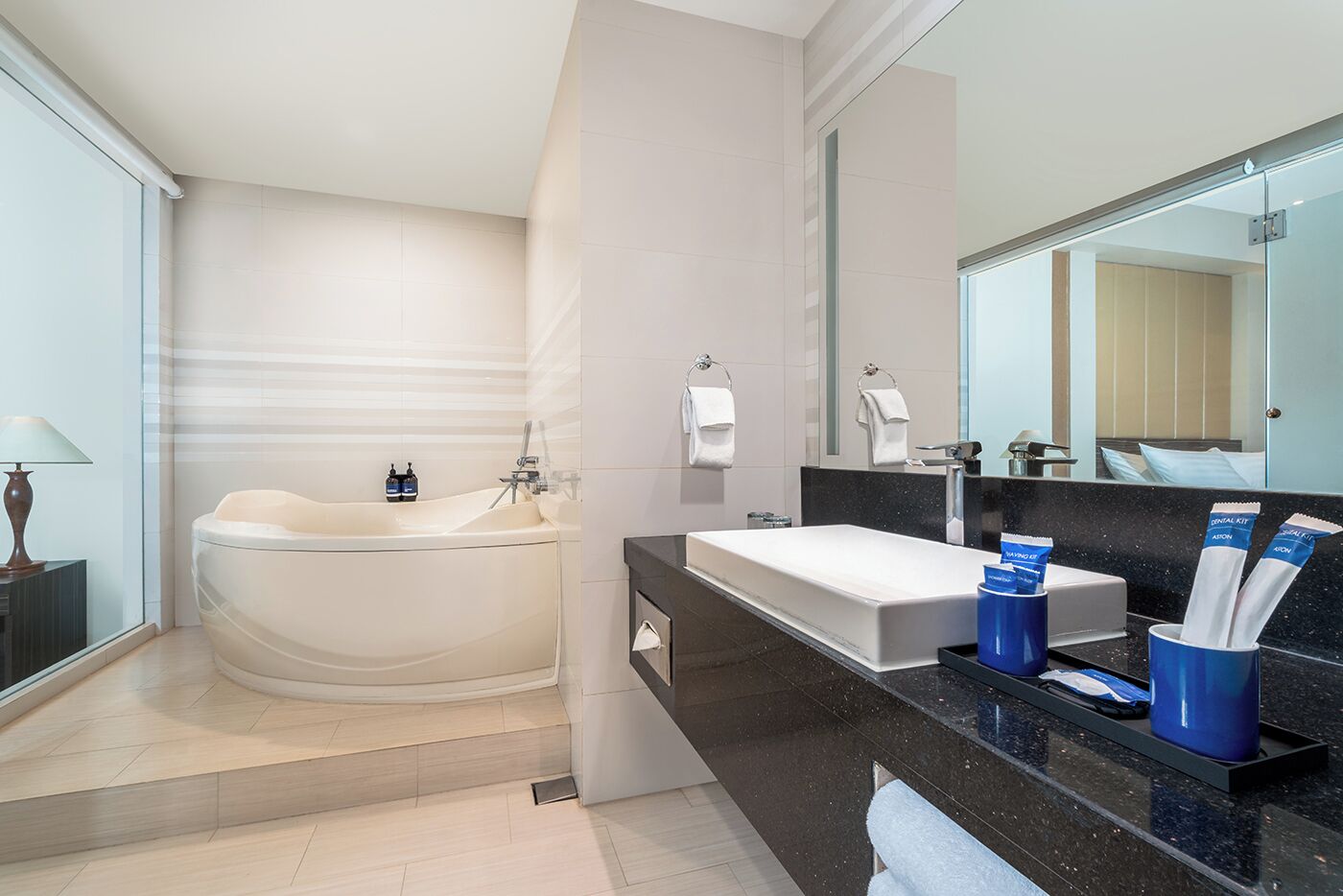 A modern bathroom with a freestanding bathtub, a large vanity with a black countertop, and a mirror above the sink.