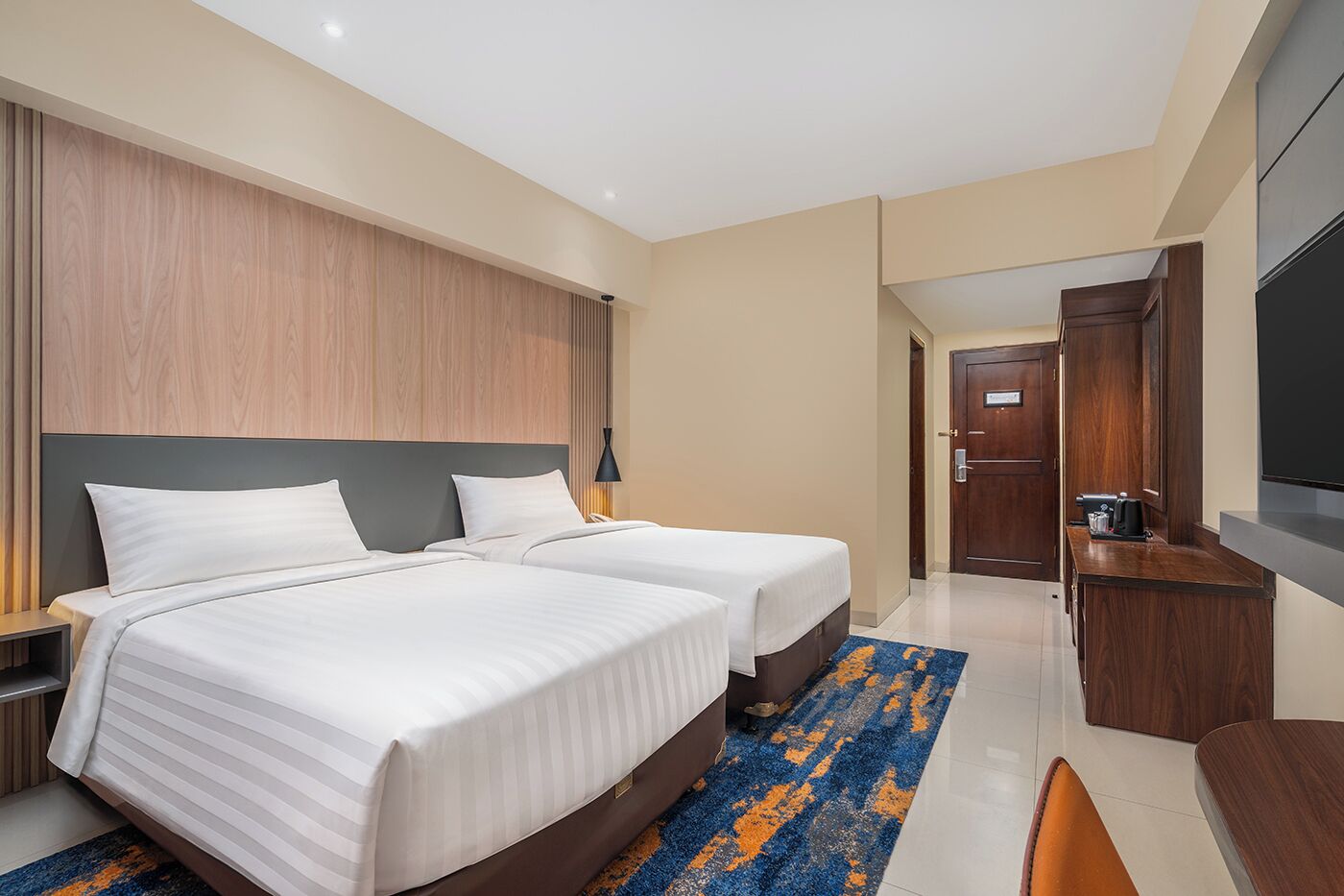 Een moderne hotelkamer met twee bedden, een bureau, een televisie en een koffiezetapparaat.