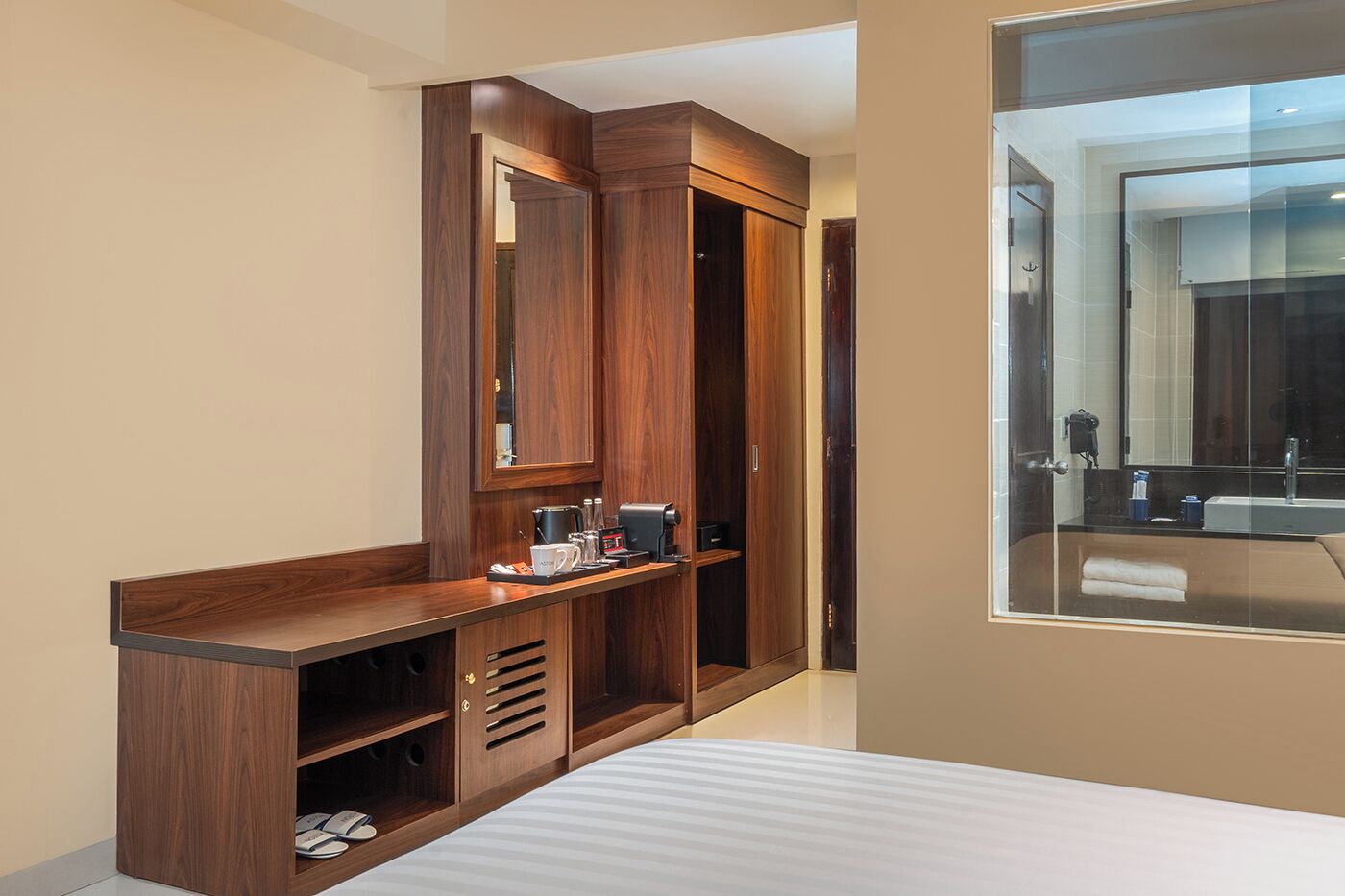 A modern hotel room with a wooden vanity, a large mirror, and a built-in wardrobe.