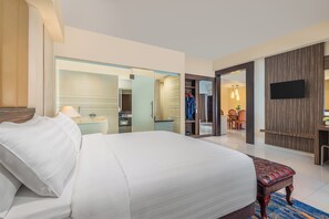 Quarto de hotel com uma cama grande, televisão, guarda-roupa e casa de banho.